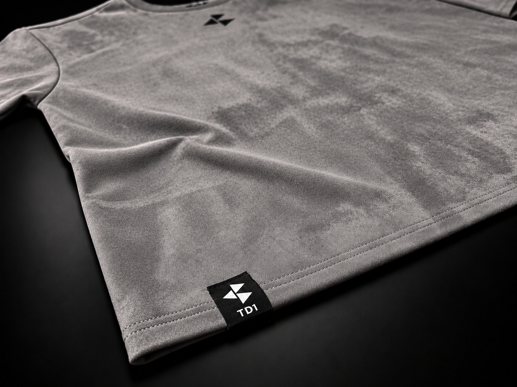 TD1WORLD Engineered Winter Tee in Charcoal Grey, close-up of stretch suede texture, stitched hem and woven TD1 label