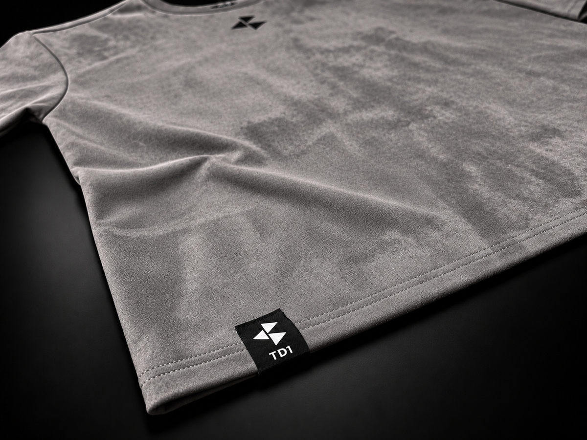 TD1WORLD Engineered Winter Tee in Charcoal Grey, close-up of stretch suede texture, stitched hem and woven TD1 label